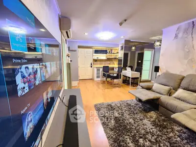 Modern living room with plush seating, smart TV, and dining area in open layout apartment.