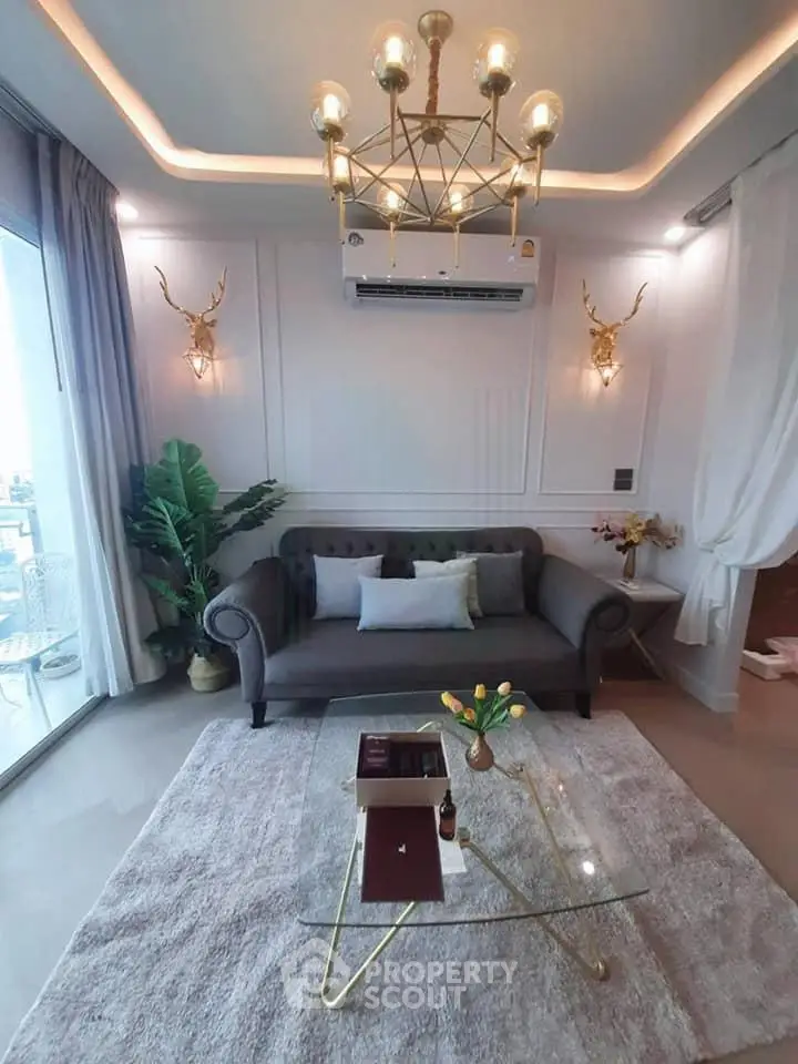 Luxurious living room with elegant chandelier and modern decor, featuring a cozy sofa and glass coffee table.