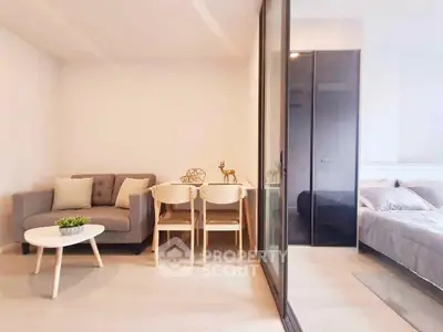 Modern studio apartment with cozy living area and bedroom separated by glass partition.