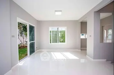 Spacious and bright living room with large windows and garden view, perfect for modern living.