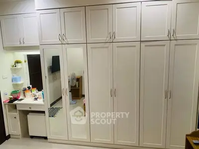 Spacious bedroom with elegant white wardrobes and vanity area