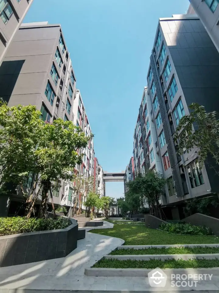 Modern apartment complex with lush green landscaping and clear blue sky