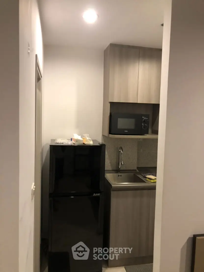 Compact modern kitchen with sleek cabinetry and appliances in a cozy apartment setting.