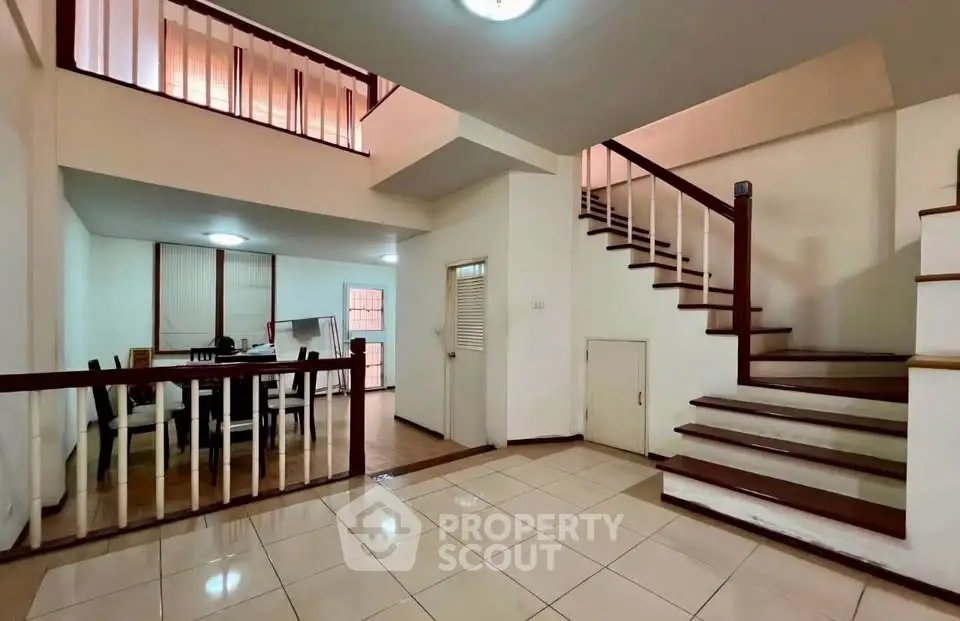 Spacious two-story interior with elegant staircase and dining area, perfect for modern living.