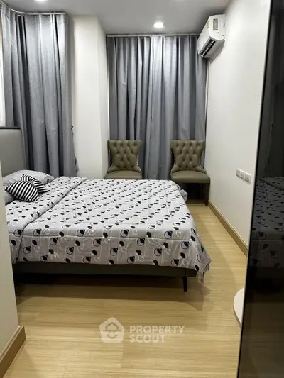 Cozy bedroom with modern decor and air conditioning, featuring elegant chairs and stylish curtains.