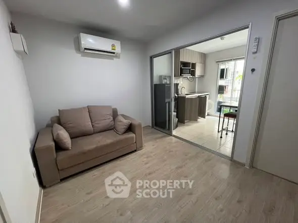 Cozy living room with air conditioning and adjacent modern kitchen