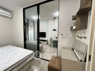 Modern studio apartment with glass partition, cozy living area, and stylish workspace.