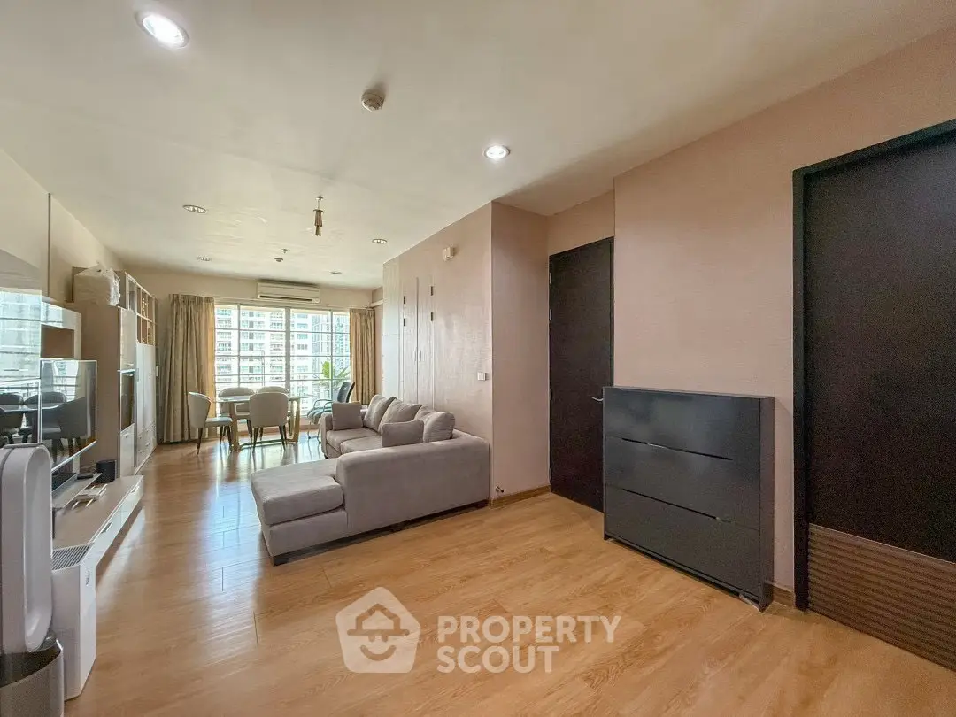 Spacious modern living room with wooden flooring and large windows offering natural light.