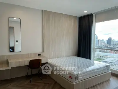 Modern bedroom with city view, featuring a stylish desk and comfortable bed.