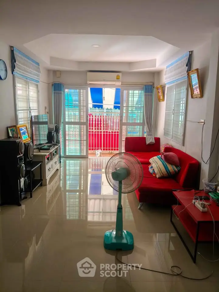 Spacious living room with modern decor and large windows leading to a balcony, perfect for relaxation.