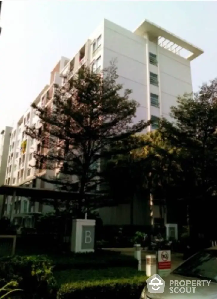 Modern residential building with lush greenery and clear sky view.