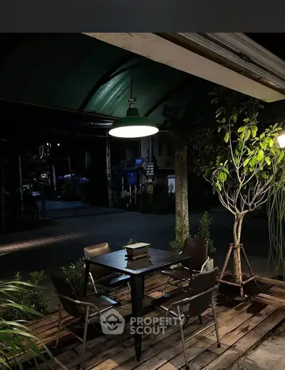 Charming outdoor seating area with ambient lighting and lush greenery.