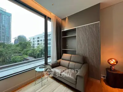 Modern living room with large window and cozy seating area overlooking greenery.