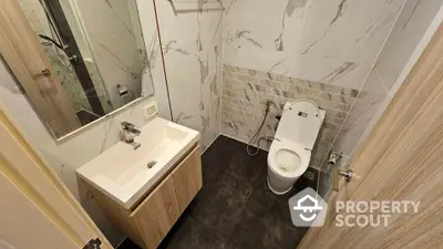 Modern bathroom with sleek fixtures and marble tiles, featuring a stylish vanity and contemporary toilet.