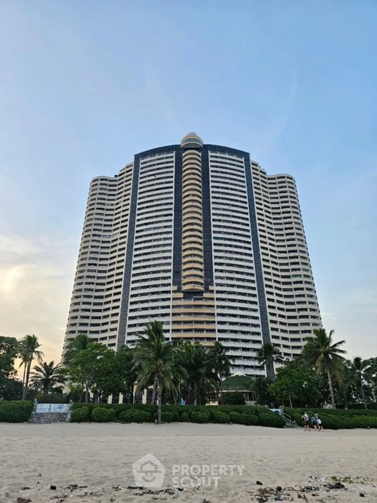 Stunning beachfront high-rise building with lush greenery and palm trees