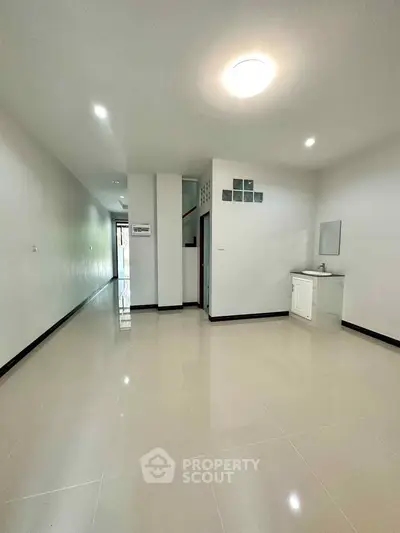 Spacious unfurnished living area with glossy tiled floors and modern lighting.