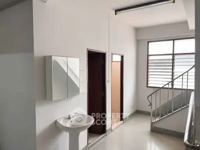Minimalist interior hallway with sink and staircase, featuring natural light from large window.