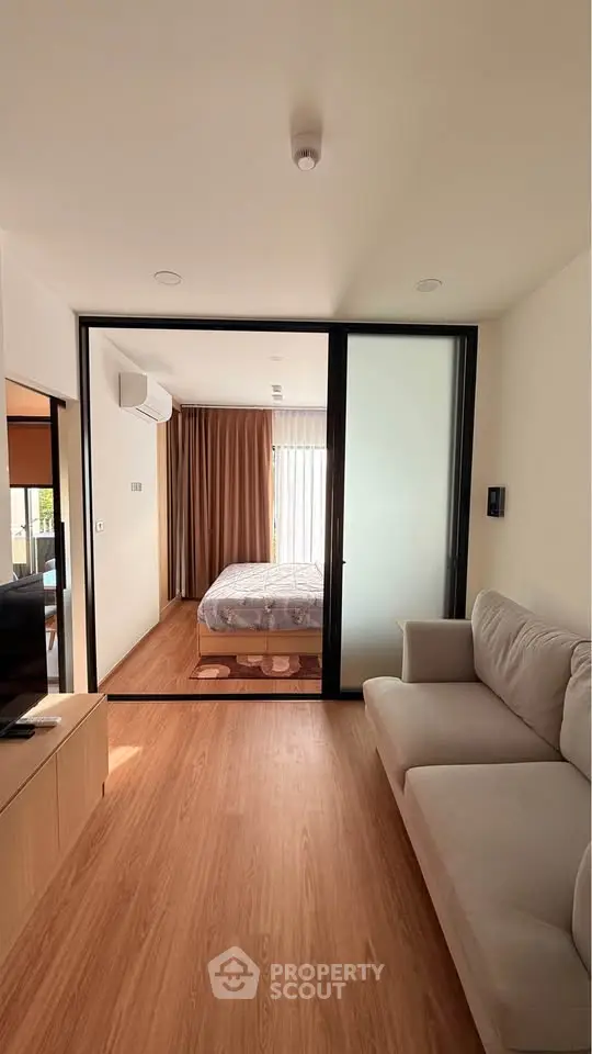 Modern apartment interior with cozy living room and bedroom separated by sliding glass doors.
