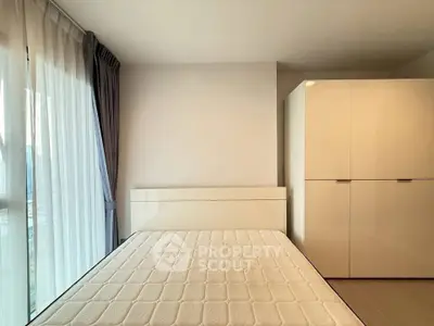 Spacious bedroom with large window and modern wardrobe in a bright apartment.