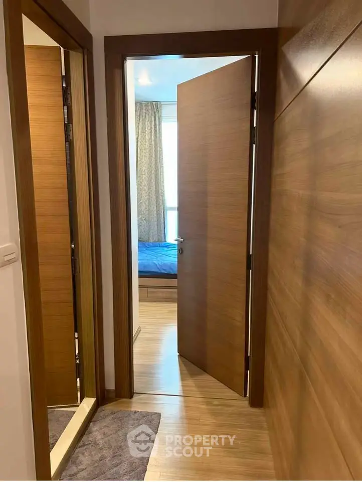 Modern apartment hallway leading to a cozy bedroom with wooden accents.