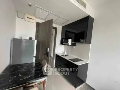 Modern compact kitchen with sleek black cabinets and integrated appliances in a stylish apartment.