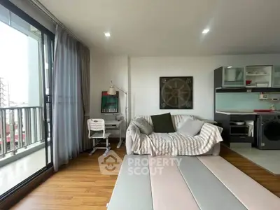 Modern living room with balcony, cozy sofa, and stylish kitchen area in open layout apartment.