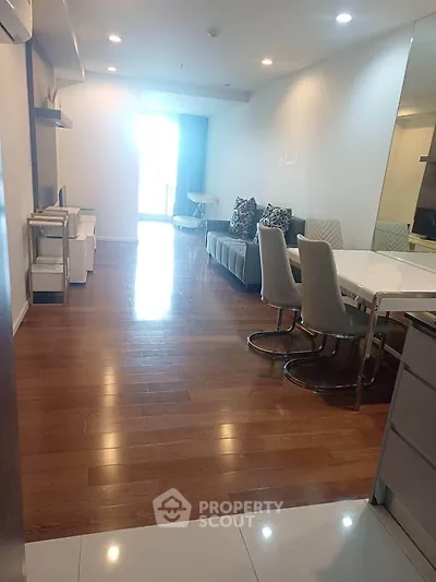 Spacious modern living room with wooden flooring and elegant dining area in a stylish apartment.