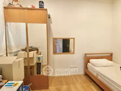Cozy bedroom with wooden flooring, single bed, and mirrored wardrobe, ideal for minimalist living.