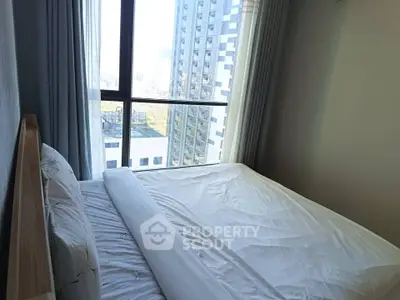 Bright bedroom with large window offering stunning city view in modern apartment.