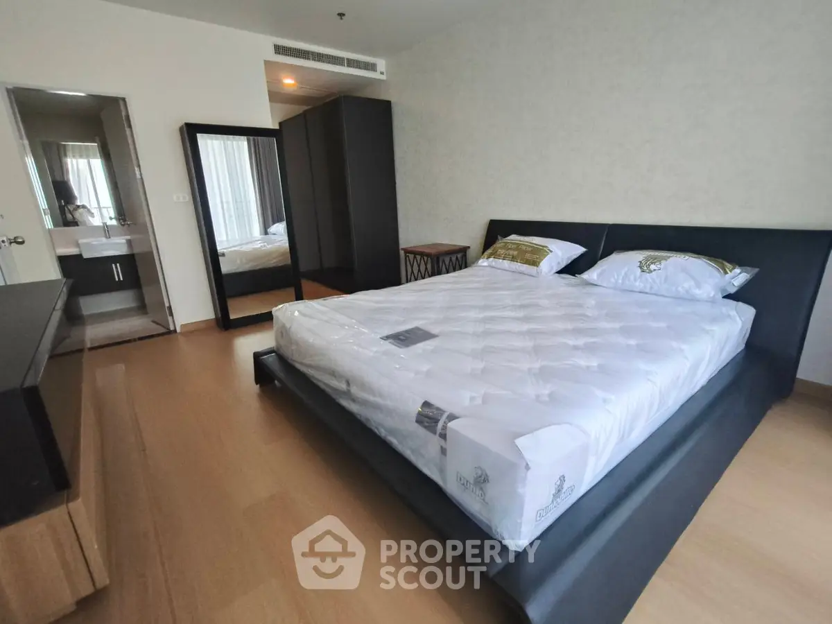 Spacious modern bedroom with sleek design and ensuite bathroom in a stylish apartment.