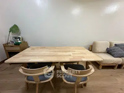 Modern dining area with wooden table and chairs, cozy sofa, and minimalist decor.