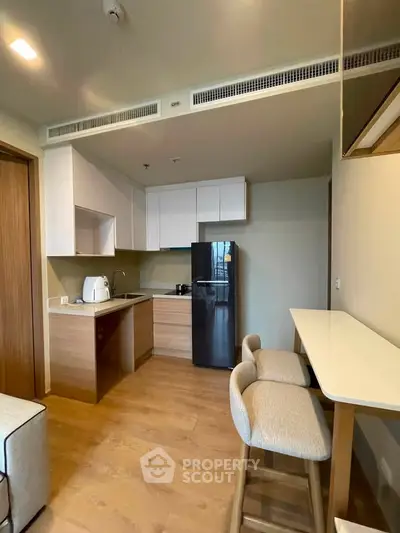 Modern kitchen with sleek cabinetry and breakfast bar in a cozy apartment setting.