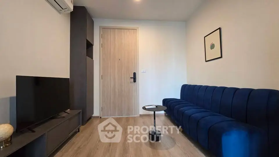 Modern living room with blue sofa, TV, and minimalist decor in a stylish apartment.