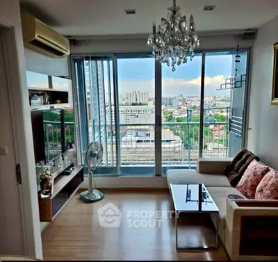Modern living room with city view, elegant chandelier, and cozy seating area.