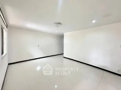Spacious empty room with white walls and tiled flooring, ready for customization.