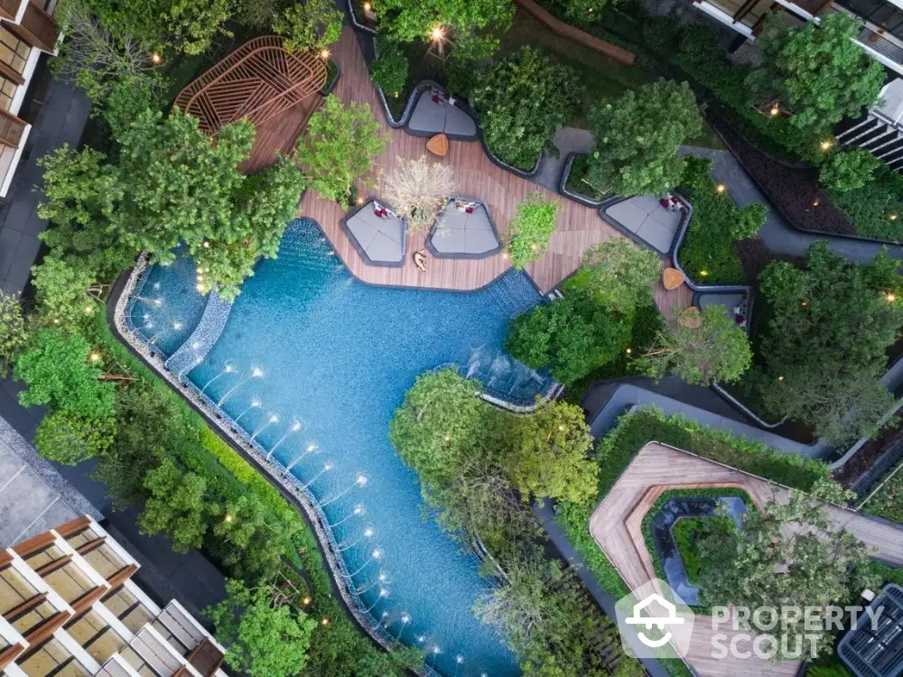 Stunning aerial view of luxurious residential pool surrounded by lush greenery and modern architecture.