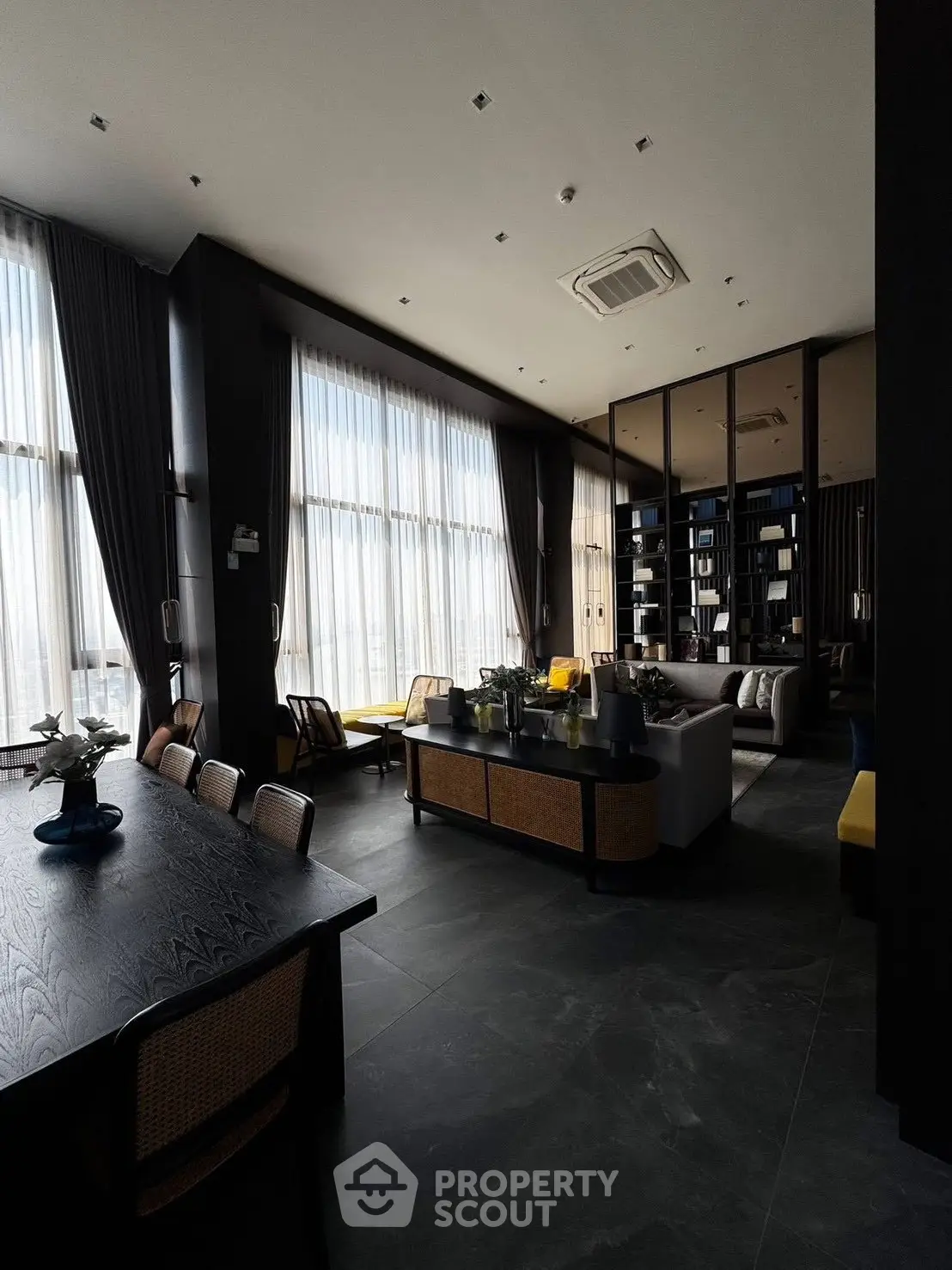 Luxurious living room with high ceilings, elegant furnishings, and large windows offering abundant natural light.