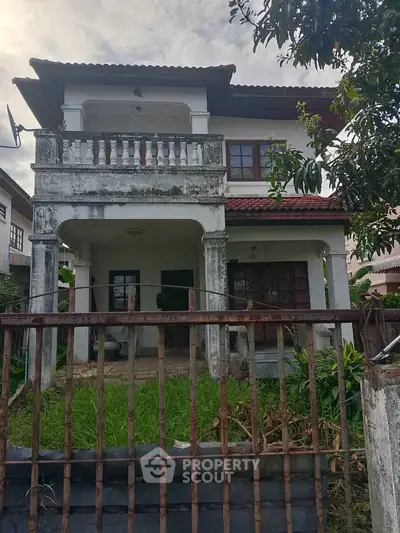 Charming two-story house with balcony and rustic exterior, perfect for renovation enthusiasts.