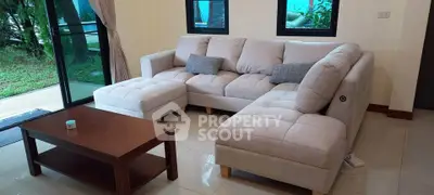 Spacious living room with modern sectional sofa and glass doors leading to garden view.