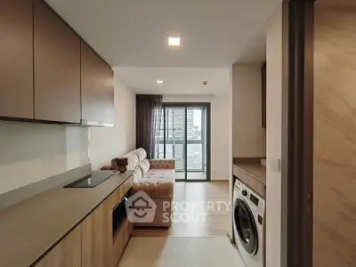 Modern apartment with open kitchen and cozy living area featuring a washing machine and city view balcony.