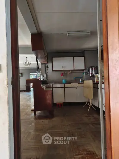 Spacious kitchen with wooden cabinetry and parquet flooring in a cozy home setting.