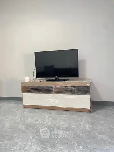 Modern living room with sleek TV stand and flat-screen TV on polished floor.