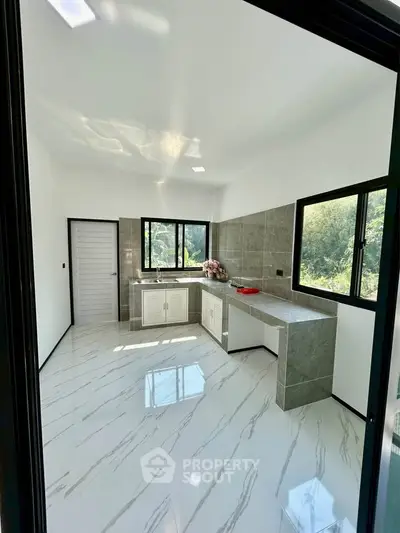Modern kitchen with sleek design and large windows offering natural light.