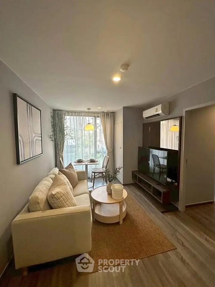 Modern living room with cozy sofa, stylish decor, and natural light from large windows.