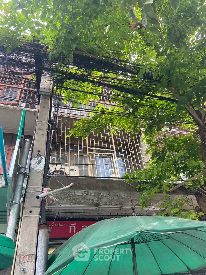 Urban building facade with lush greenery and utility wires