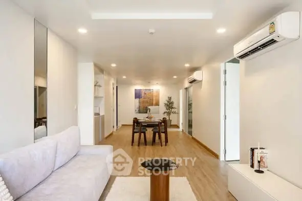 Spacious modern living room with elegant decor and dining area, featuring air conditioning and stylish furniture.