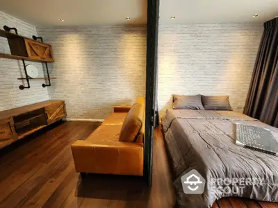 Chic modern bedroom with sleek wooden flooring, cozy bed, and stylish brick wall accents, perfect for urban living.