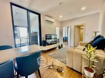 Modern living room with cozy seating and stylish decor, featuring a playful cat on wooden flooring.