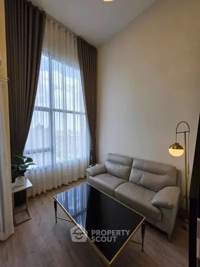 Elegant living room with high ceilings, large window, and modern furniture in a luxury apartment.