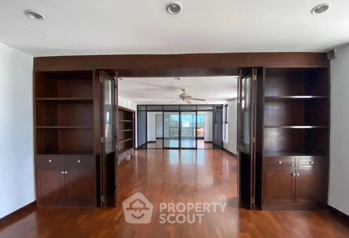 Spacious living room with wooden flooring and built-in shelves, ideal for modern living.